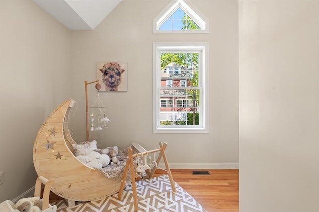sitting room featuring vaulted ceiling, baseboards, visible vents, and wood finished floors