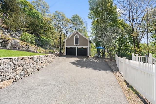 garage with fence, a garage, and aphalt driveway
