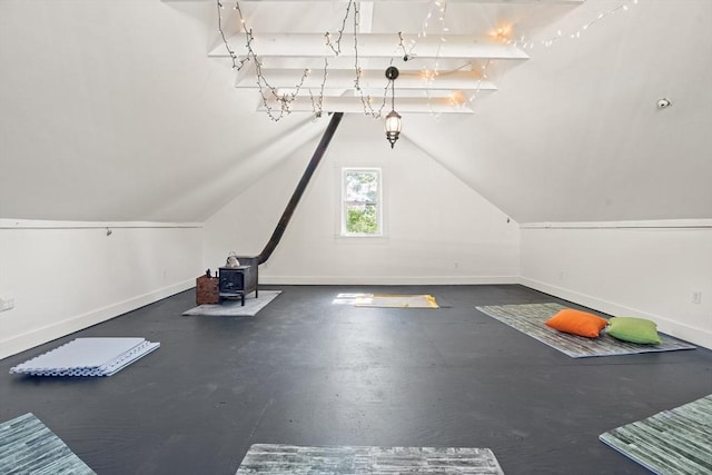 workout area with baseboards, a wood stove, and vaulted ceiling