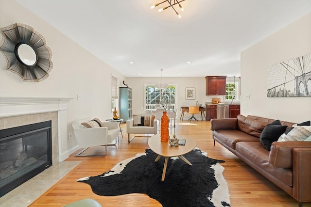 living area with a notable chandelier, a fireplace, recessed lighting, and light wood-style floors