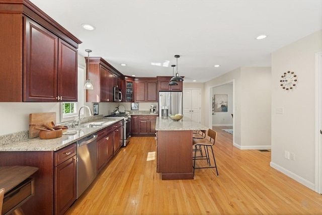 kitchen featuring a sink, light wood finished floors, stainless steel appliances, and baseboards