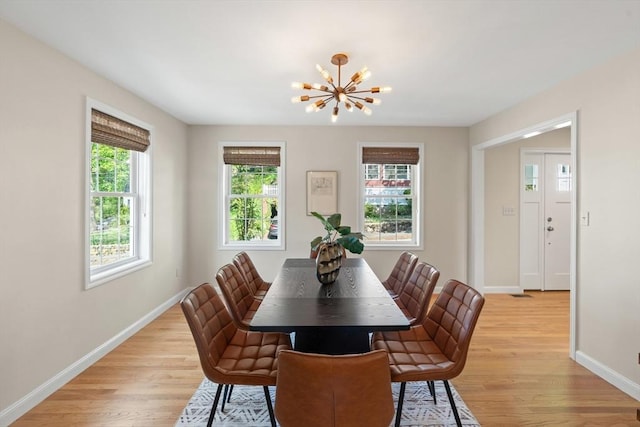 dining space featuring light wood-style flooring, a notable chandelier, and baseboards