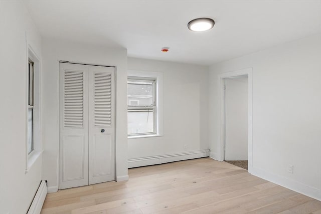71 Water St, Quincy, MA 02169 - unfurnished bedroom featuring a baseboard radiator, light wood-style flooring, and a closet