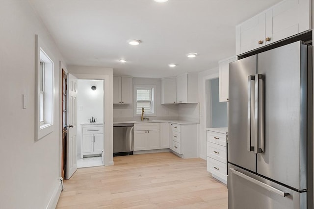 71 Water St, Quincy, MA 02169 - kitchen featuring stainless steel appliances, light wood-type flooring, light countertops, a sink, and white cabinets