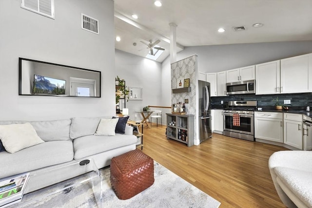 living room featuring ceiling fan, visible vents, and light wood finished floors