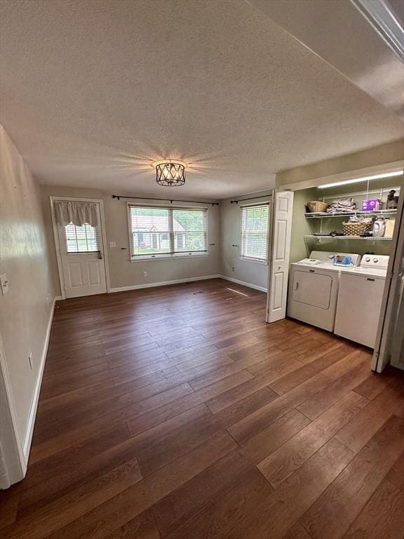 17 Walnut St, Gill, MA 01354 - unfurnished living room with washing machine and dryer, dark wood-type flooring, baseboards, a textured ceiling, and plenty of natural light