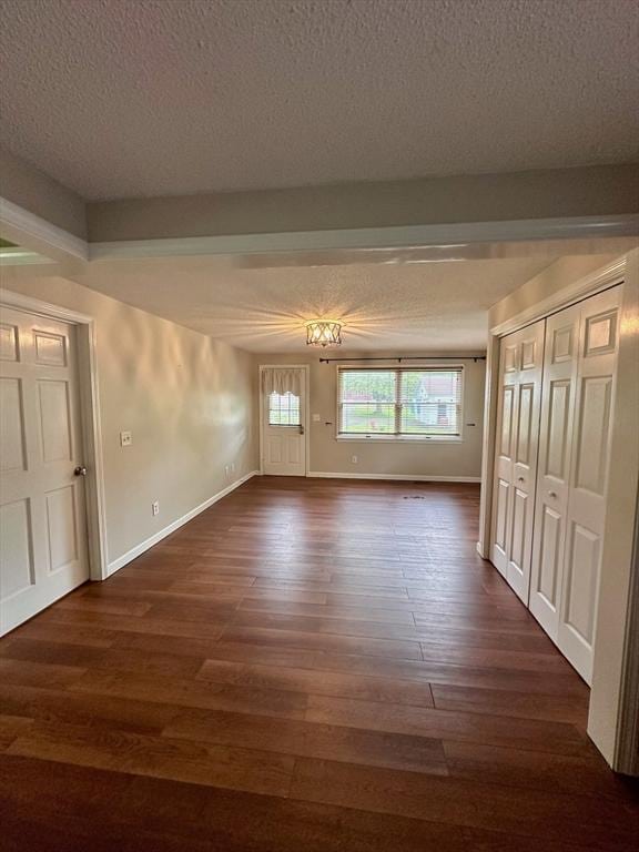 17 Walnut St, Gill, MA 01354 - unfurnished living room with a textured ceiling, dark wood-type flooring, baseboards, and beam ceiling