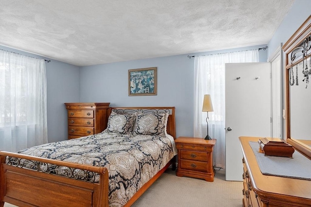 bedroom featuring light carpet and a textured ceiling