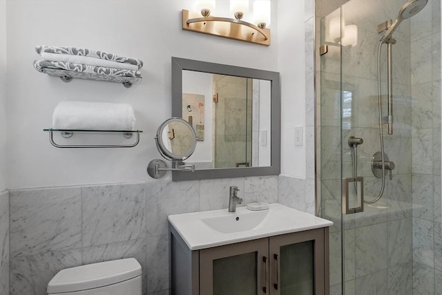 bathroom featuring vanity, a shower stall, toilet, and tile walls