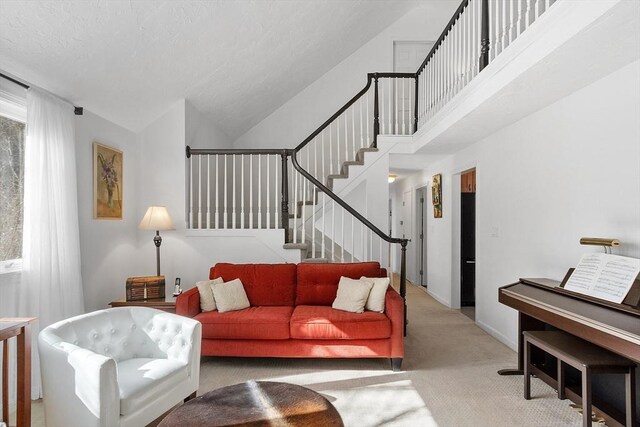 living room featuring light carpet, high vaulted ceiling, baseboards, and stairway