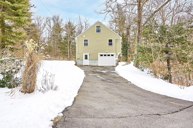 view of snow covered exterior featuring driveway and an attached garage