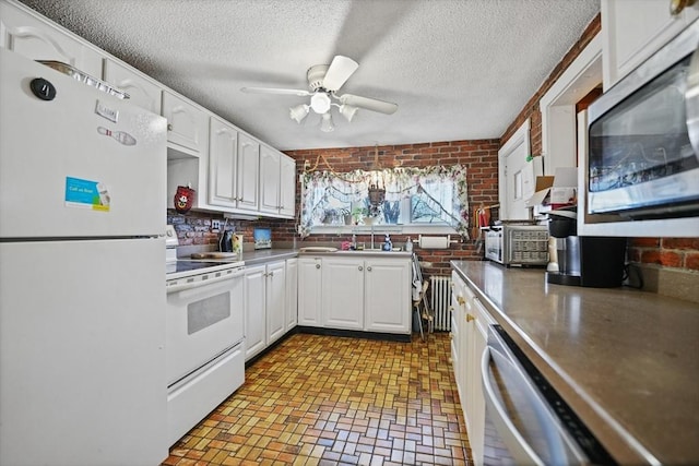 kitchen featuring ceiling fan, white cabinets, white appliances, a textured ceiling, and brick wall