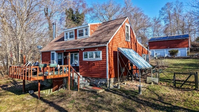 back of property with a wooden deck, a lawn, and an outdoor structure