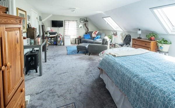 bedroom with a skylight, carpet, vaulted ceiling, and a wood stove