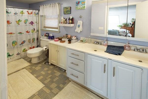 full bath with double vanity, toilet, and a shower with shower curtain