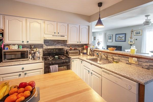 kitchen featuring dishwasher, black gas stove, under cabinet range hood, stainless steel microwave, and a sink