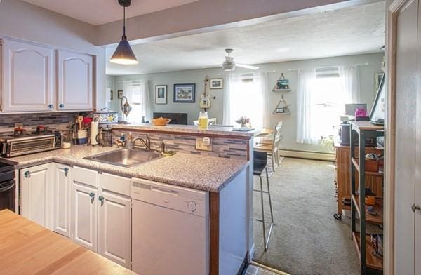 kitchen with dishwasher, a sink, a peninsula, baseboard heating, and ceiling fan