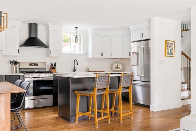 108 Central St, Ipswich, MA 01938 - kitchen with stainless steel appliances, wall chimney exhaust hood, a kitchen bar, and light countertops