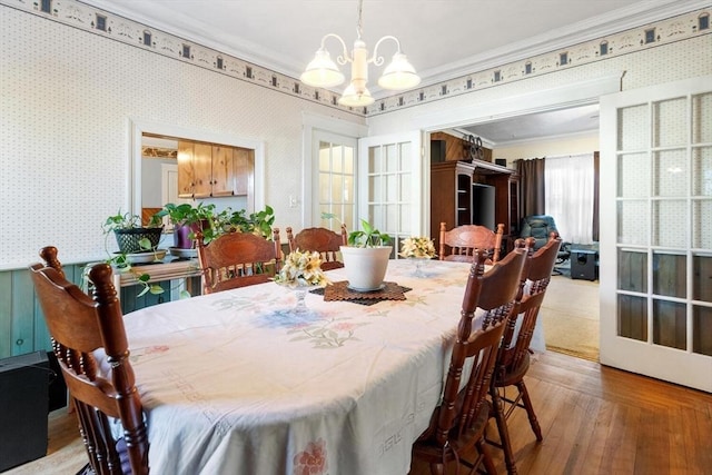 dining space with a notable chandelier, ornamental molding, and hardwood / wood-style floors