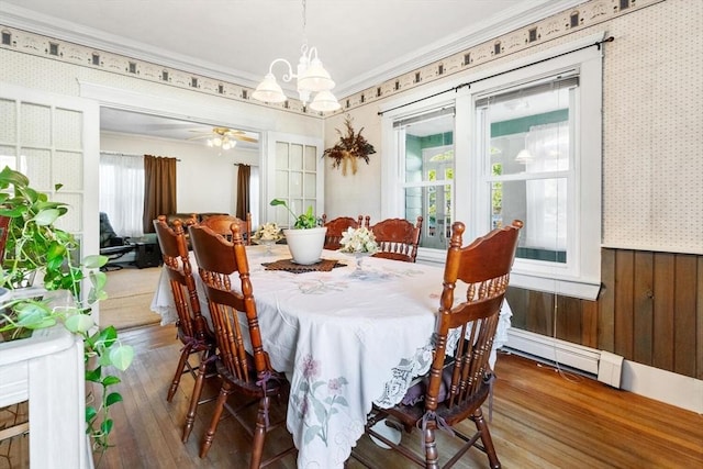 dining space featuring wood-type flooring, ceiling fan with notable chandelier, ornamental molding, and a baseboard radiator