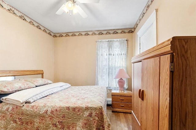 bedroom with ceiling fan, light hardwood / wood-style floors, and a baseboard radiator