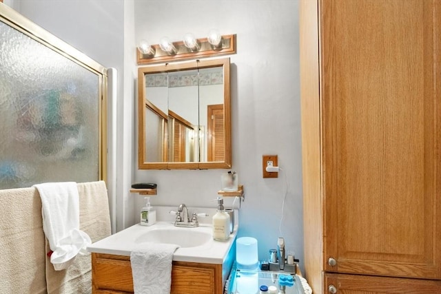 bathroom featuring a shower with shower door and vanity