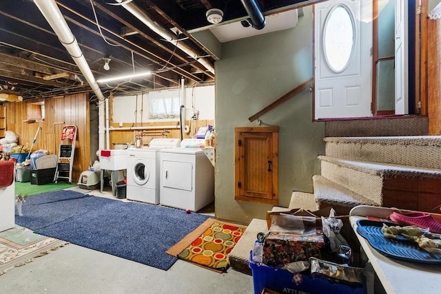 clothes washing area featuring independent washer and dryer and wooden walls