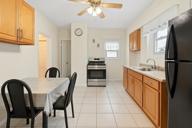 kitchen featuring freestanding refrigerator, stainless steel range with electric cooktop, a sink, a ceiling fan, and light countertops