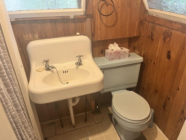 bathroom featuring tile patterned floors, toilet, and wood walls