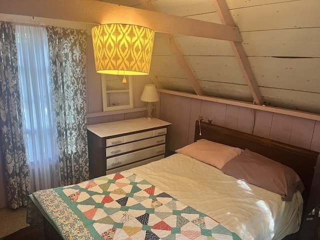 bedroom with wooden walls and lofted ceiling with beams