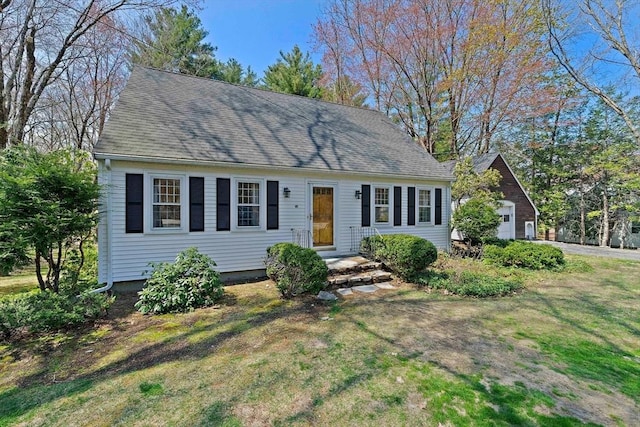 cape cod-style house featuring a garage, a shingled roof, and a front lawn