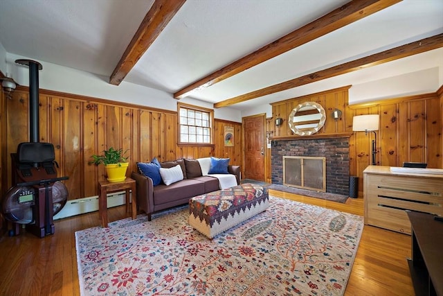 living area with light wood finished floors, wooden walls, a fireplace, and beamed ceiling