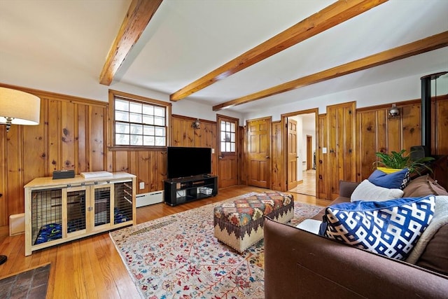 living room featuring wood-type flooring, wood walls, beam ceiling, and a baseboard radiator