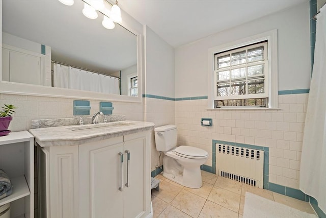 bathroom with vanity, radiator, wainscoting, tile walls, and tile patterned floors