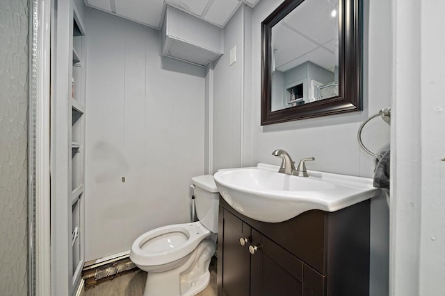 half bath with vanity, built in features, wood finished floors, and toilet