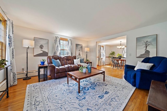 living area featuring light wood finished floors, a baseboard heating unit, and a chandelier