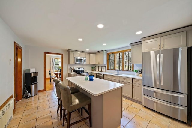 kitchen with a sink, light countertops, radiator, stainless steel appliances, and recessed lighting