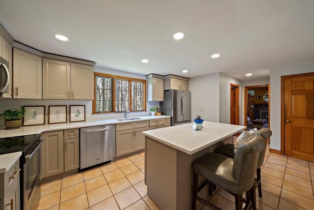 kitchen featuring a kitchen breakfast bar, light countertops, a sink, light tile patterned floors, and stainless steel appliances