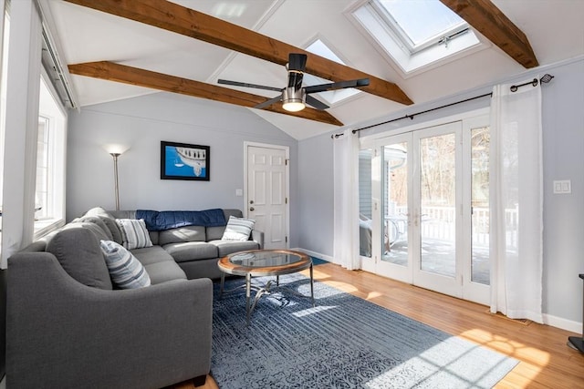 living room with hardwood / wood-style flooring, lofted ceiling with skylight, a wealth of natural light, and french doors