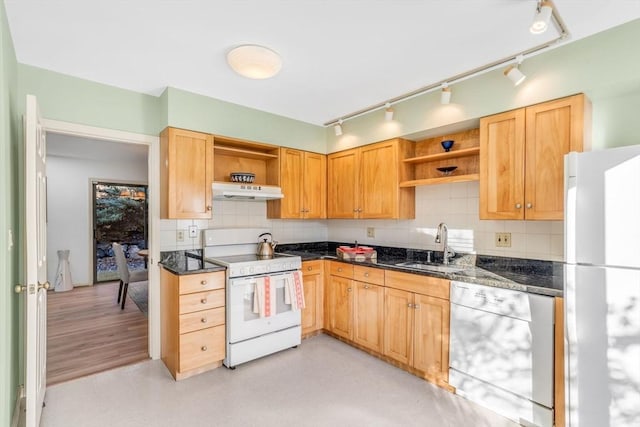 kitchen with white appliances, backsplash, dark stone counters, and sink