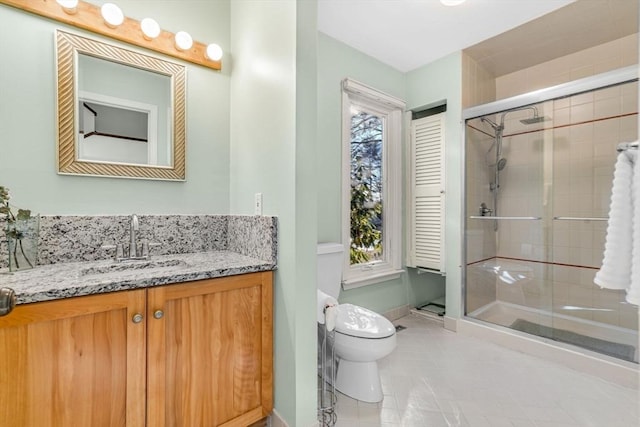 bathroom with tile patterned floors, vanity, toilet, and a wealth of natural light