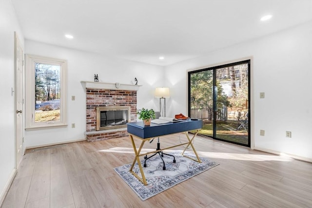 office space featuring light hardwood / wood-style floors and a brick fireplace