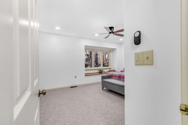 living area with carpet and ceiling fan