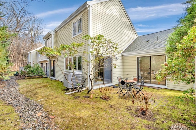 rear view of property with central AC unit and a yard