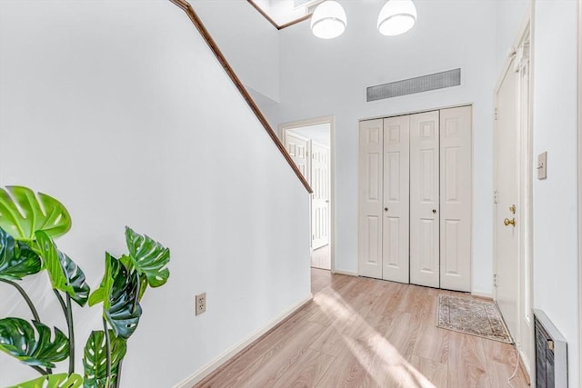 entryway featuring light wood-type flooring and a towering ceiling