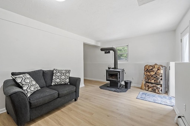 525 Flat Hill Rd, Lunenburg, MA 01462 - living area featuring light wood-type flooring, a wood stove, baseboards, and a baseboard radiator