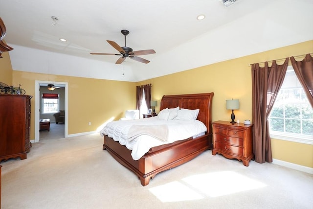 bedroom featuring a raised ceiling, lofted ceiling, light colored carpet, and ceiling fan