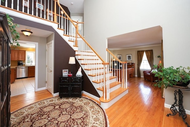 stairway with hardwood / wood-style flooring, ornamental molding, and a high ceiling