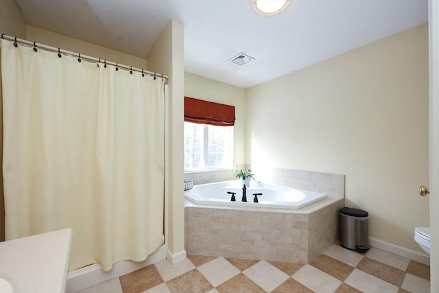 bathroom with a relaxing tiled tub and toilet