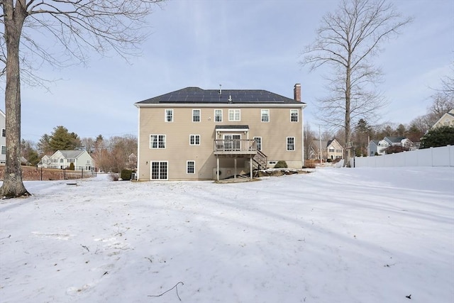 snow covered rear of property with a deck